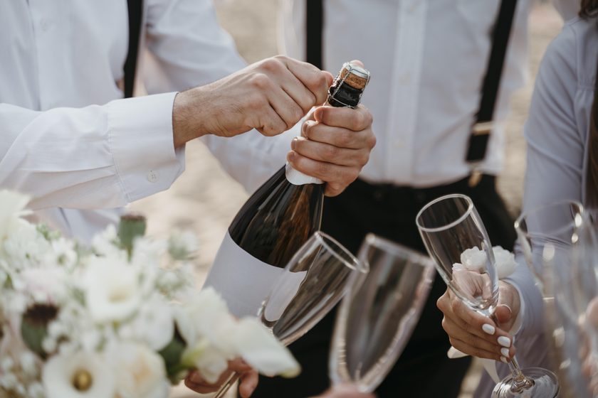 Eine Flasche Sekt wird für die wartenden Gläser geöffnet