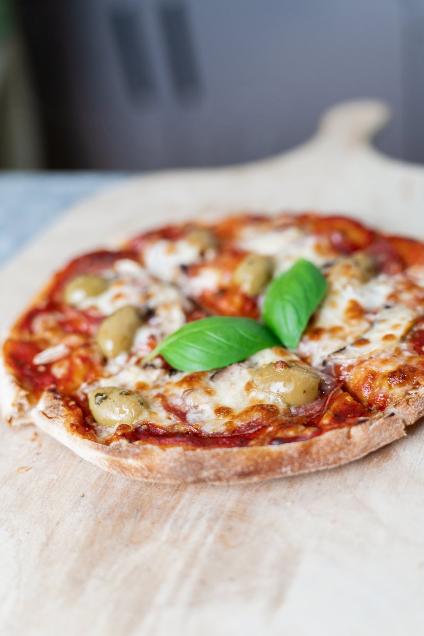 Frisch gebackene Pizza auf dem Holzschieber